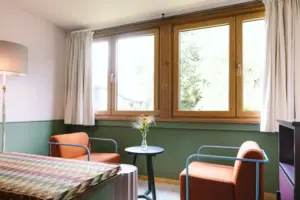 Un'area salotto con due poltrone davanti alla finestra nella camera d'albergo Chambre dell'HENRI Hotel Garmisch-Partenkirchen.