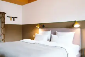 Un letto accogliente in una moderna camera d'albergo dell'HENRI Hotel Garmisch-Partenkirchen.