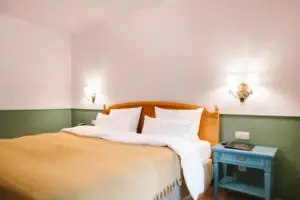 Una camera d'albergo dell'HENRI Hotel Garmisch-Partenkirchen con un letto davanti a una parete verde e bianca.