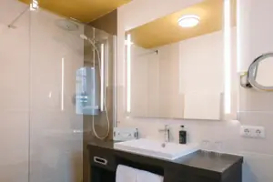 Bagno con lavabo e specchio presso l'HENRI Hotel Garmisch-Partenkirchen.