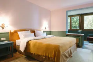 Una camera d'albergo dell'HENRI Hotel Garmisch-Partenkirchen con un letto davanti a una parete verde e bianca.