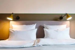 Un letto con cuscini bianchi e una lampada all'HENRI Hotel Garmisch-Partenkirchen.