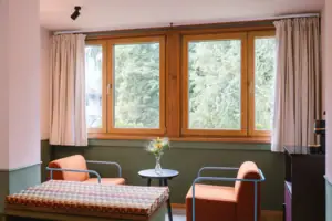 Un'area salotto con due poltrone davanti alla finestra nella camera d'albergo Chambre dell'HENRI Hotel Garmisch-Partenkirchen.