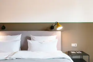 Un letto con cuscini bianchi davanti a una parete bicolore nell'HENRI Hotel Garmisch-Partenkirchen.