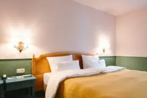 La camera d'albergo Chambre con balcone dell'HENRI Hotel Garmisch-Partenkirchen con un letto davanti a una parete verde e bianca.